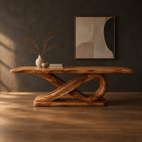 Rectangular dining table with a thick plank top on a sculpted loop base in a dark studio against a charcoal plaster wall