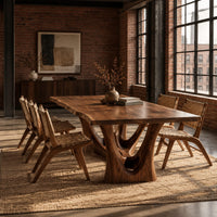 Dining table with a flared wavy top and a carved arch pedestal in an industrial loft dining room with exposed brick