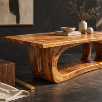 Corner detail of rectangular dining table with a thick slab top on a hollowed oval base beside wood, brass and linen samples