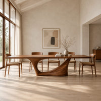 Long dining table on a single swept pedestal with an open arch in a bright open plan dining room