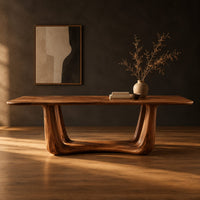 Dining table with a smooth top on an open u frame base in a dark studio against a charcoal plaster wall