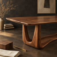 Corner detail of dining table with a smooth top on an open u frame base beside wood, brass and linen samples