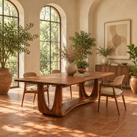 Dining table with a smooth top on an open u frame base in a bright dining room with arched windows and plants