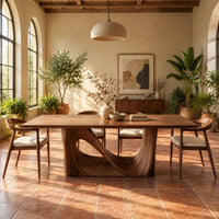 Dining table with a smooth rectangular top and a wave sculpted base in a bright dining room with arched windows and plants