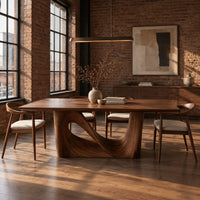 Dining table with a smooth rectangular top and a wave sculpted base in an industrial loft dining room with exposed brick