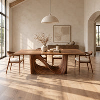 Dining table with a smooth rectangular top and a wave sculpted base in a bright open plan dining room