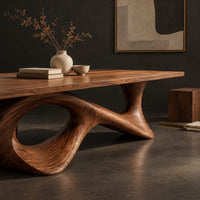 Corner detail of long dining table on a sweeping ribbon base with one large oval opening beside wood, brass and linen samples