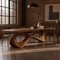 Long dining table on a sweeping ribbon base with one large oval opening in an industrial loft dining room with exposed brick