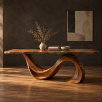 Dining table with a single sweeping wave base under a long slab top in a dark studio against a charcoal plaster wall