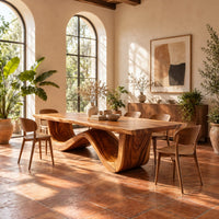 Dining table with a thick plank top on one sculpted wave base in a bright dining room with arched windows and plants