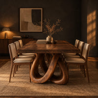 Dining table with two knotted loop pedestals and a thick slab top in a dark dining room at golden hour