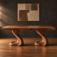 Dining table with two sculpted pedestal legs and a thick flat top in a dark studio against a charcoal plaster wall