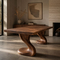 Corner detail of dining table with two sculpted pedestal legs and a thick flat top beside wood, brass and linen samples
