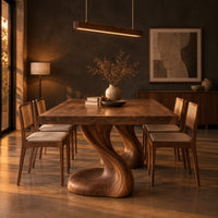 Dining table with two sculpted pedestal legs and a thick flat top in a dark dining room at golden hour