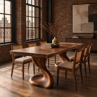 Dining table with two sculpted pedestal legs and a thick flat top in an industrial loft dining room with exposed brick
