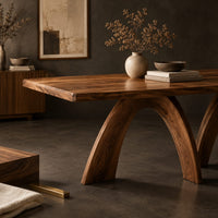 Corner detail of dining table with twin sculpted arch legs and a smooth slab top beside wood, brass and linen samples