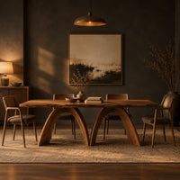 Dining table with twin sculpted arch legs and a smooth slab top in a dark dining room at golden hour