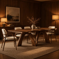 Dining table with twin sculpted arch legs and a smooth slab top in an evening dining room with walnut wall paneling