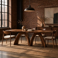 Dining table with twin sculpted arch legs and a smooth slab top in an industrial loft dining room with exposed brick