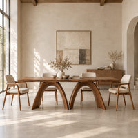 Dining table with twin sculpted arch legs and a smooth slab top in a bright open plan dining room