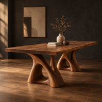 Dining table with a thick plank top on two sculpted loop pedestals, three-quarter view showing the grain
