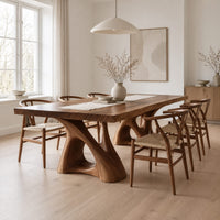Dining table with a thick plank top on two sculpted loop pedestals in a Scandinavian dining room with white walls