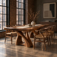 Dining table with a thick plank top on two sculpted loop pedestals in an industrial loft dining room with exposed brick
