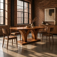 Rectangular dining table with two flared pedestals on a shared low plinth in an industrial loft dining room with exposed brick