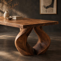 Corner detail of rectangular dining table on two sculpted legs that form a teardrop gap beside wood, brass and linen samples