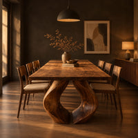 Rectangular dining table on two sculpted legs that form a teardrop gap in a dark dining room at golden hour