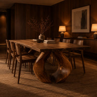 Rectangular dining table on two sculpted legs that form a teardrop gap in an evening dining room with walnut wall paneling