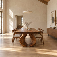 Rectangular dining table on two sculpted legs that form a teardrop gap in a bright open plan dining room