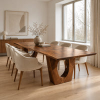 Long dining table on two heavy pedestals with arched openings in a Scandinavian dining room with white walls