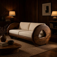 Sofa with thick circular wooden arms, hollow cutouts and cream seat cushions in an evening living room with walnut wall paneling