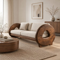 Sofa with thick circular wooden arms, hollow cutouts and cream seat cushions in a Scandinavian living room with white walls