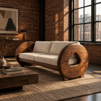 Sofa with thick circular wooden arms, hollow cutouts and cream seat cushions in an industrial loft living room with exposed brick