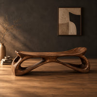 Bench with a dished seat and sculpted legs with oval cutouts in a dark studio against a charcoal plaster wall