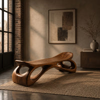 Bench with a dished seat and sculpted legs with oval cutouts in an industrial loft entryway with exposed brick