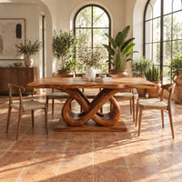 Dining table with a wavy edged slab top and a double infinity loop base in a bright dining room with arched windows and plants