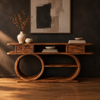 Console table with a double loop base and two small drawers in a dark studio against a charcoal plaster wall