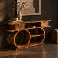 Corner detail of console table with a double loop base and two small drawers beside wood, brass and linen samples