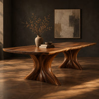 Dining table with a long top and two flared sculpted pedestals, three-quarter view showing the grain