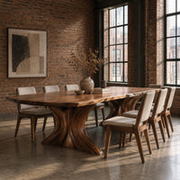 Dining table with a long top and two flared sculpted pedestals in an industrial loft dining room with exposed brick