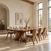 Dining table with a long top and two flared sculpted pedestals in a bright open plan dining room
