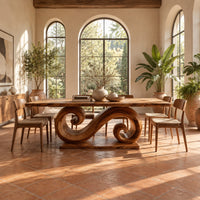 Dining table with a double scroll pedestal on a flat plinth in a bright dining room with arched windows and plants