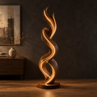 Twisting double ribbon floor lamp with a warm glow in a dark studio against a charcoal plaster wall
