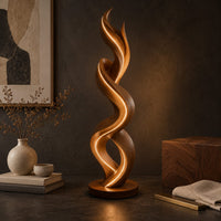 Corner detail of twisting double ribbon floor lamp with a warm glow beside wood, brass and linen samples