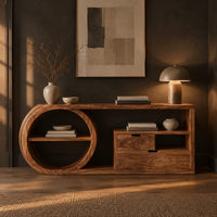 Console table with a drum shaped shelf end, two drawers and an open cubby in a dark entryway at golden hour