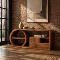Console table with a drum shaped shelf end, two drawers and an open cubby in an industrial loft entryway with exposed brick