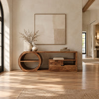 Console table with a drum shaped shelf end, two drawers and an open cubby in a bright open plan entryway